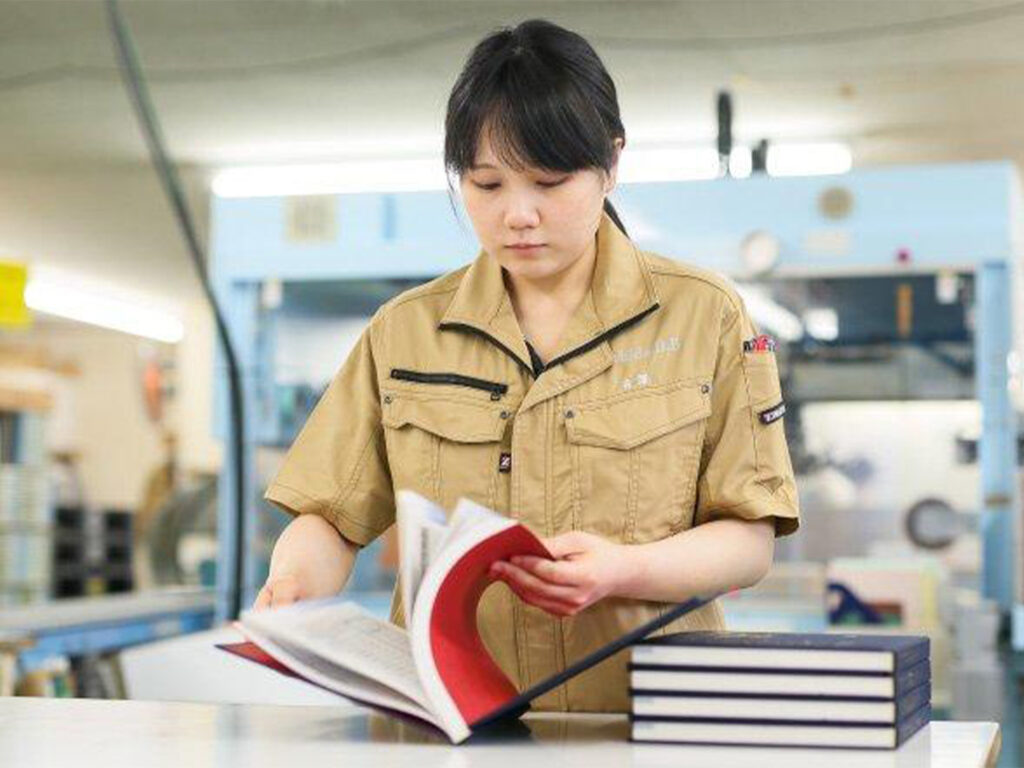 Técnico de impresión que revisa los libros terminados para comprobar la calidad de la producción